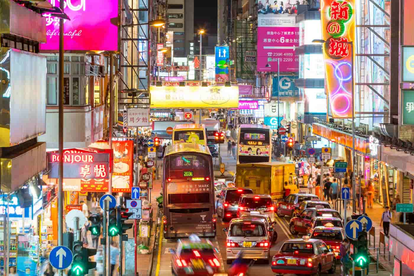 Busy Hong Kong street at night lit with colorful neon signs and heavy traffic