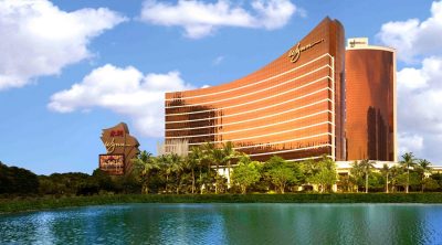 Wynn Macau resort exterior with curved bronze-toned facade overlooking a lake