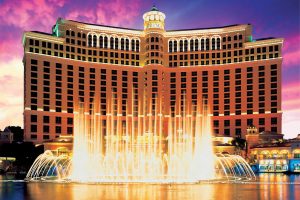 Bellagio hotel facade in Las Vegas with its fountains illuminated at dusk