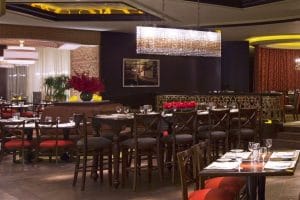 Elegant restaurant dining area with dark wood décor and red seating.