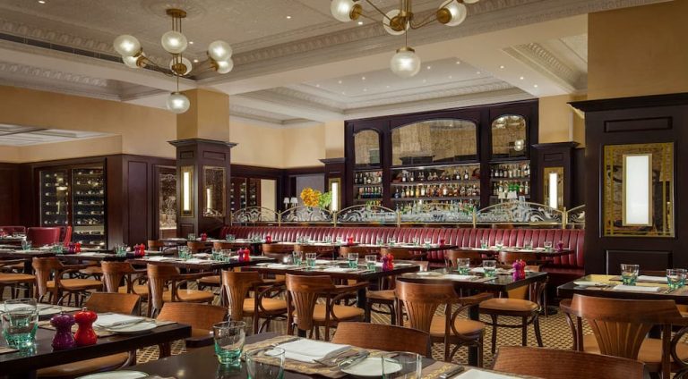 Upscale restaurant interior with red banquette seating and bar.